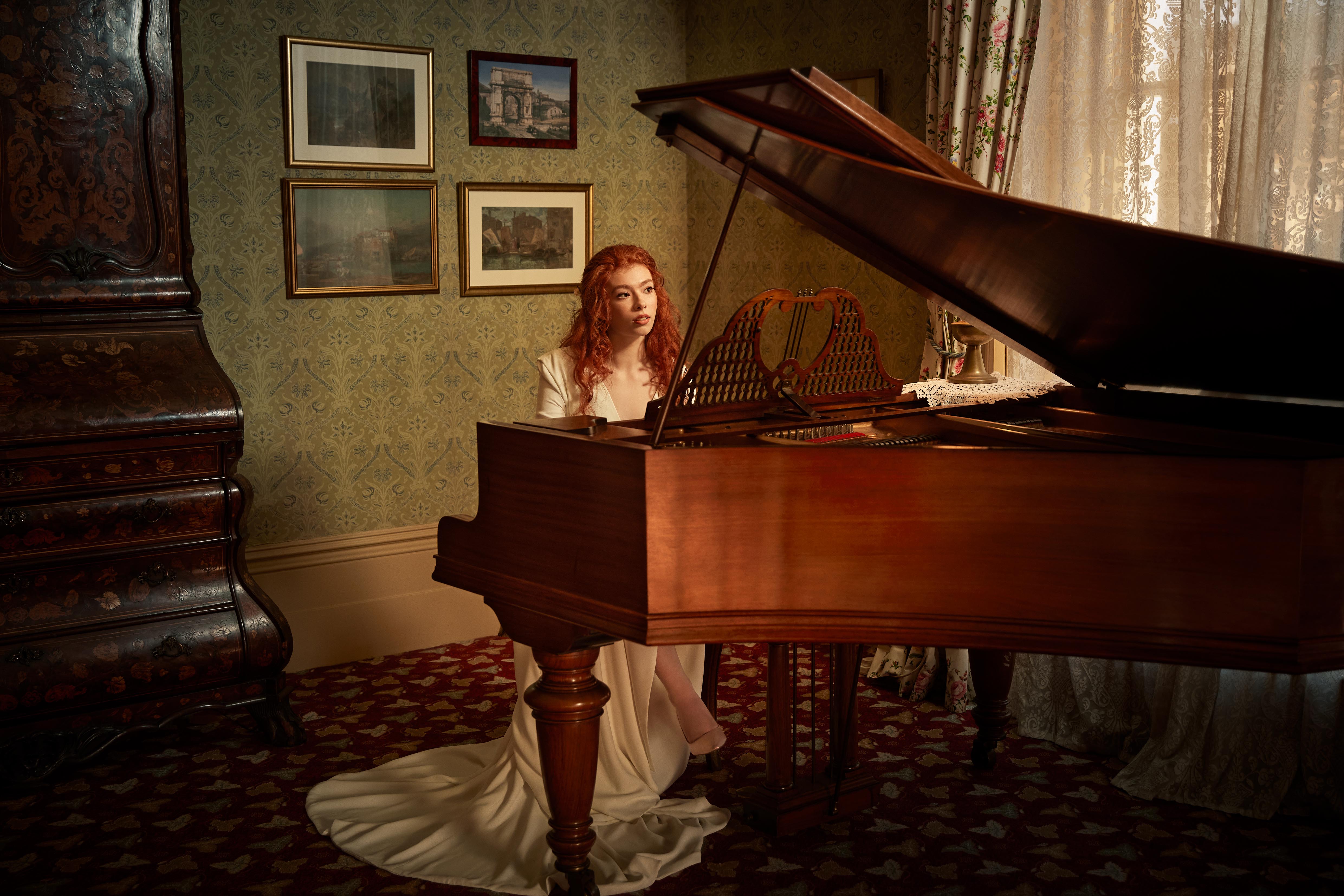 Beautiful red haired bride plays piano